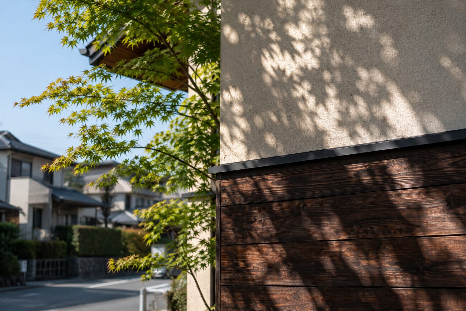 年月の経過と外壁の質感が美しい住宅コーナーと木漏れ日の影｜時代の基準変更と既存不適格のイメージ