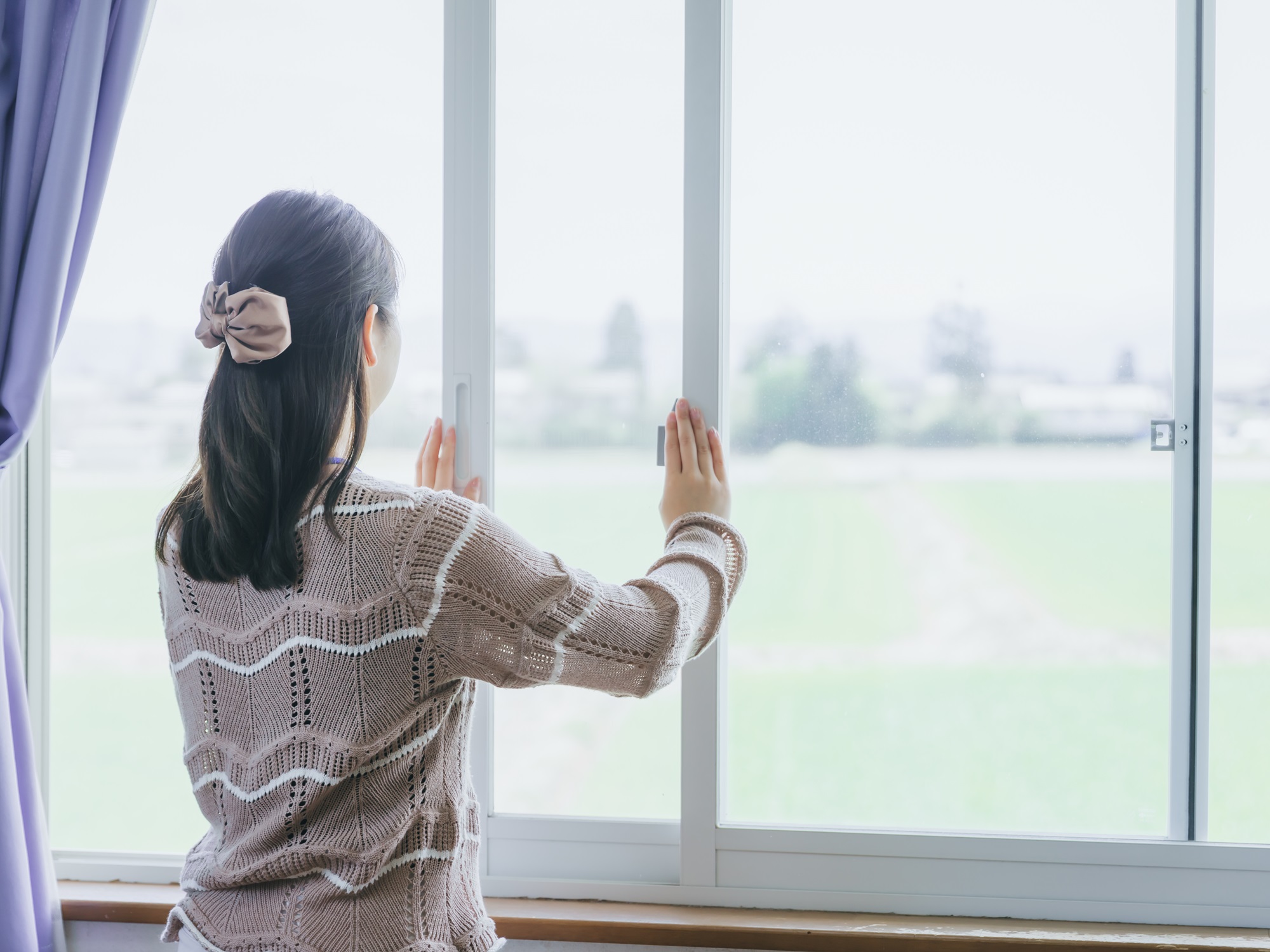 換気のために窓を開けている女性