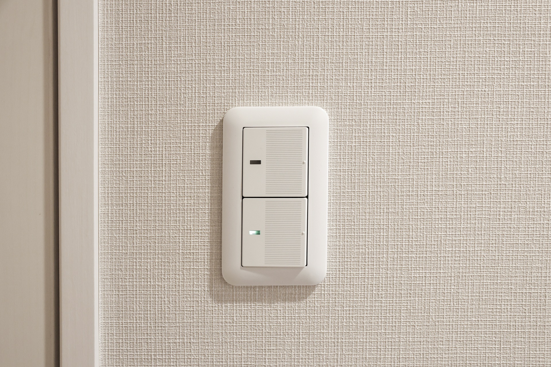 白い壁に設置された一般的な縦型2連のワイドスイッチ(ホタルスイッチ)