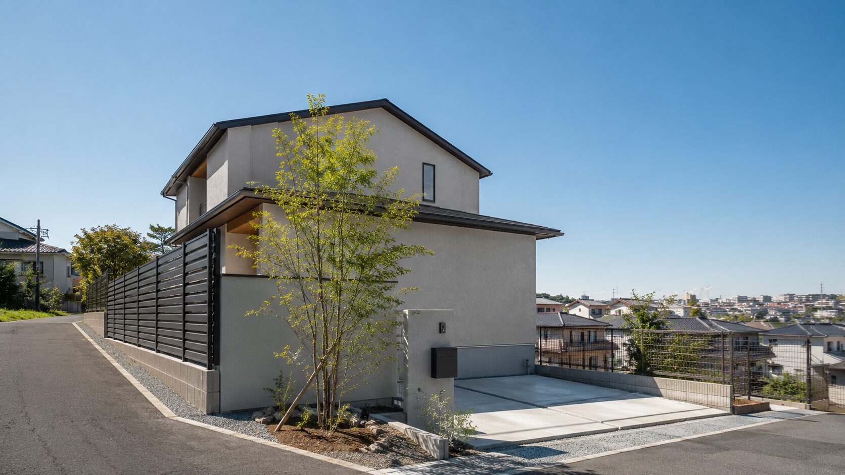 地盤調査や付帯工事費に影響する横浜の緩やかな坂道沿いにある住宅の敷地と境界フェンスのイメージ画像